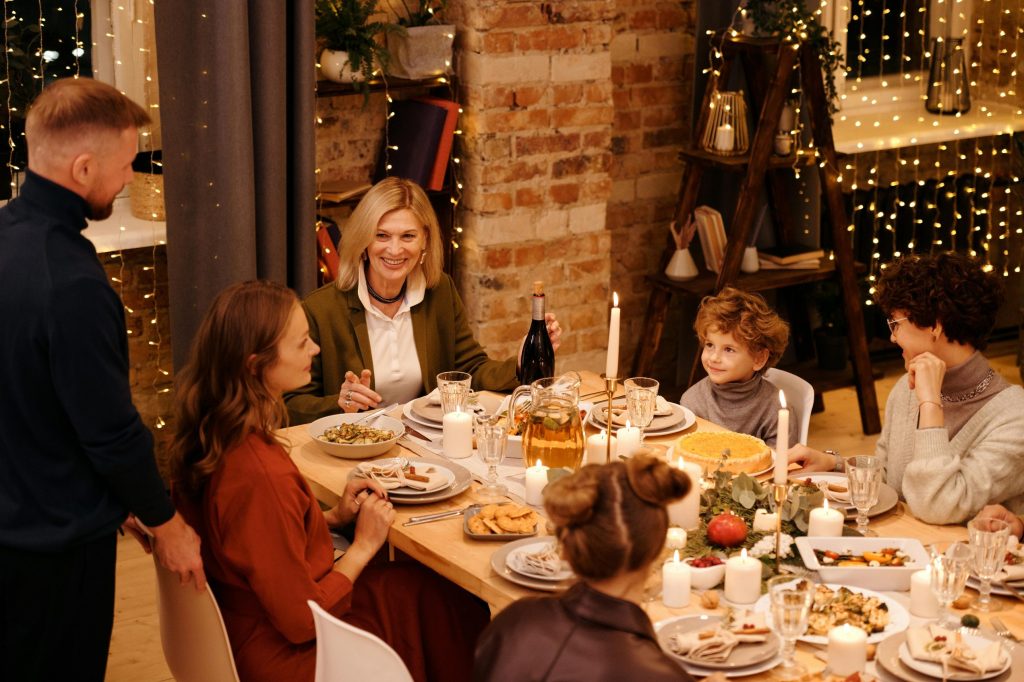 Warm family gathering enjoying Christmas dinner with festive decor and lights.